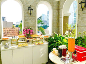 Bàn tiệc với bánh mini phối màu xanh và trắng, cùng logo công ty, phù hợp hội nghị