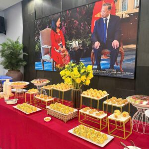 Bàn teabreak với bánh mini xếp hàng ngay ngắn, có điểm nhấn trang trí bằng hoa quả và lá bạc hà